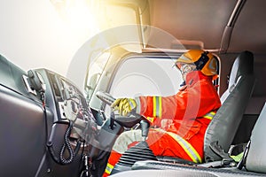Confident mature fireman driving fire truck with communication interior view at station