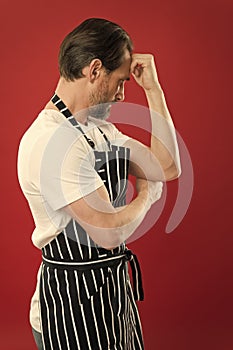 Confident mature handsome man in apron red background. He might be baker gardener chef or cleaner. Good in everything