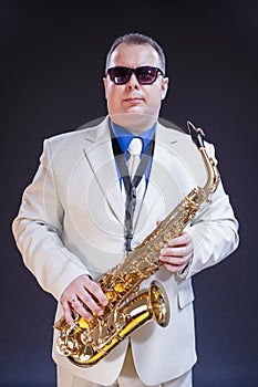 Confident Mature Male Saxophonist Posing with Instrument in White Suit and Sunglasses