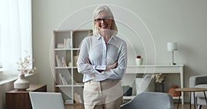 Confident mature senior professional woman in glasses standing at laptop