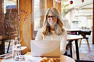 Confident mature woman sitting in the cafe and using her laptop