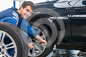 Confident Mechanic Changing Car Tire At Automobile Shop