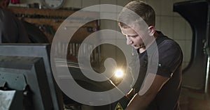 Confident mechanic typing on tire changer's control desk on auto service