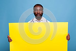 Confident medic with stethoscope holding large yellow empty banner