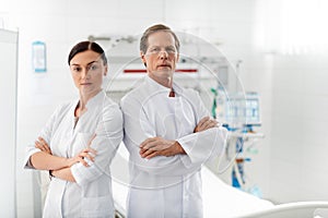 Confident medical workers with crossed arms posing in hospital room