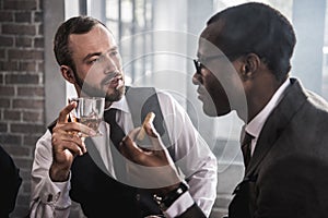 Confident men with cigar and glass of alcohol beverage talking