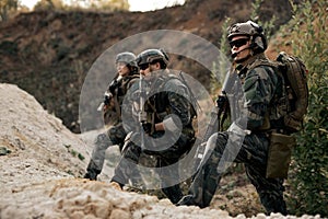 Confident men, special forces soldiers with rifles standing together looking at side