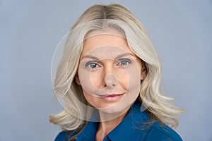 Confident mid aged business woman looking at camera isolated on grey, headshot.