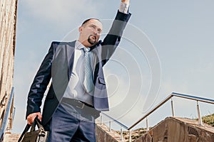 Confident middle age businessman with briefcase walking upstairs. Close-up of businessman wearing blue suit holding bag