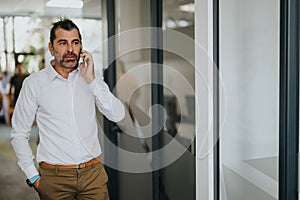 Confident middle-aged businessman negotiating a deal on the phone in office.