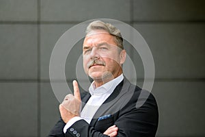 Confident middle aged businessman pointing upwards with finger