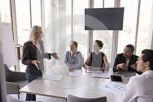 Confident middle aged female boss talking to diverse employees