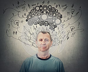 Confident middle aged man, brainstorming concept, has a cogwheel brain above head. Senior male mental health, positive thinking