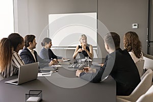 Confident middle aged team leader woman meeting with diverse group