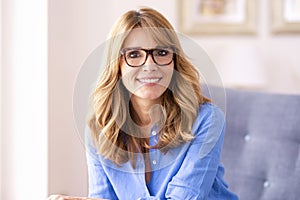 Confident middle aged woman portrait while siting in armchair