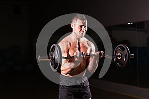 Confident muscular man training with barbell . Closeup portrait of professional bodybuilder workout with barbell at gym.