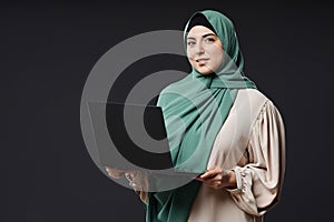 Confident Muslim Woman Holding Laptop and Smiling as Female IT Professional