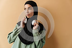 A confident muslim woman wearing black hijab holding her headphones