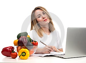 Confident nutritionist woman working at desk with fresh fruits a