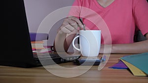 A confident office employee having tea / coffee while working on a laptop