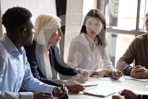 Confident older female boss team leader talking to focused workers.