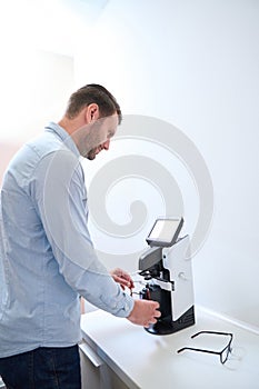 Confident optometrist is installing lenses on the frame on the modern machine