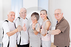 Confident people showing thumbs up at healthclub