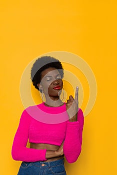 Confident And Perky Young Black Woman In Neon Color Pink Sweater Is Pointing Up