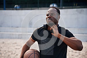 Confident person. Young black man is with basketball ball outdoors