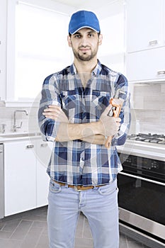 Confident plumber is standing in the kitchen