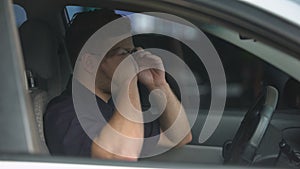 Confident policeman sitting in patrol car and wearing sunglasses, ready for work