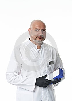 Confident portrait of a handsome male doctor, plastic surgeon wearing black gloves and holding a package of medicines