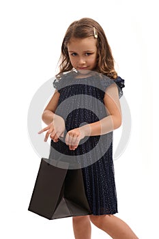 Confident portrait isolated on white background with copy space of pretty baby girl looking at camera with black shopping packet