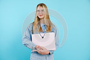 Confident, powerful, smiling blonde teenage girl in glasses holding paper folder, portfolio. Back to school, university