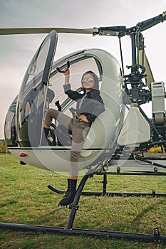 Confident preteen girl in mirrored sunglasses standing on footboard of helicopter