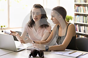 Confident pretty college achiever girl helping classmate with assignment