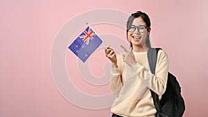 Confident pretty girl showing a New Zealand flag on pink isolated background, education concept