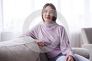 Confident pretty girl sittig on sofa in her apartment