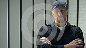 Confident prison security guard looking to camera standing near cell, profession