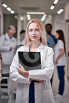 Confident Professional Female Doctor Posing At Camera Holding Clipboard in Hands