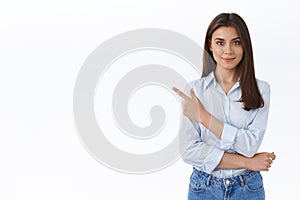 Confident professional young woman in blue blouse pointing finger upper left corner and looking at camera persuade