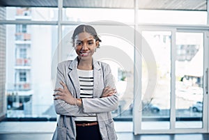 Confident, proud and professional young black business woman folding her arms and smiling in a modern office. Portrait