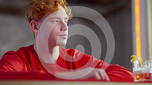 Confident redhead Caucasian young man hanging up phone and ordering drink in pub. Portrait of carefree millennial