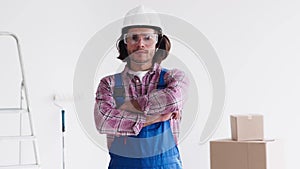 Confident renovation handyman wearing uniform with protective glasses and helmet looking at camera