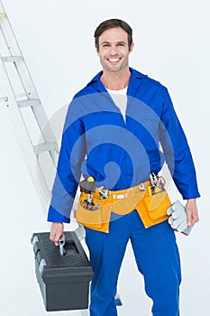 Confident repairman carrying tool box