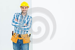 Confident repairman leaning on blank billboard