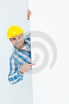 Confident repairman pointing at blank billboard