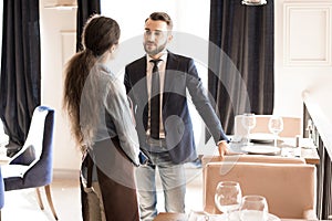 Confident restaurateur listening to waitress