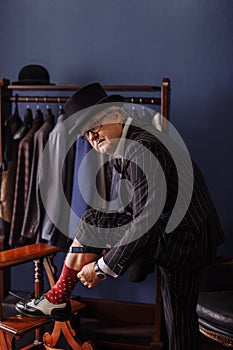 Confident retro style fashion man sitting on wooden stool tailor`s workshop