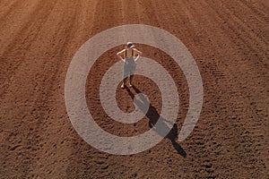 Confident satisfied female farmer standing on ploughed field, drone pov